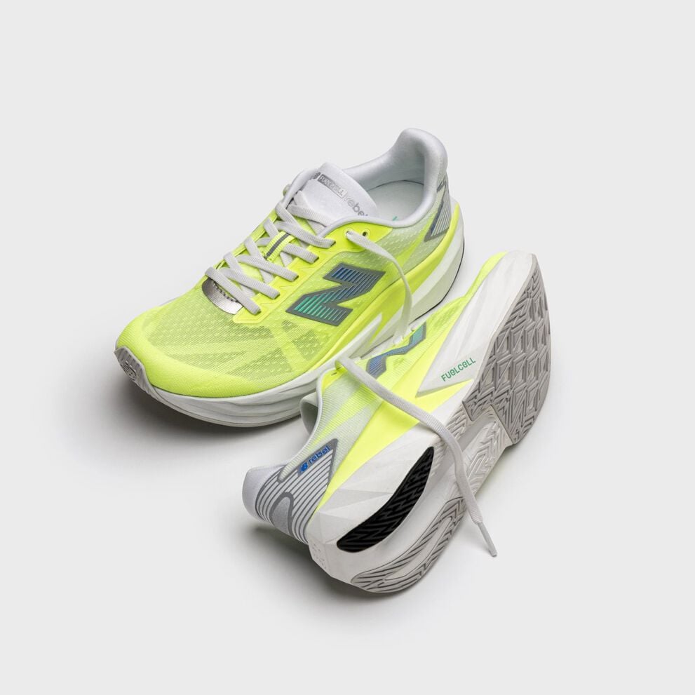 Pair of lime‑yellow running shoes with white midsoles and blue New Balance logos, displayed on a light gray background with one shoe upright and the other tilted to show the outsole. 