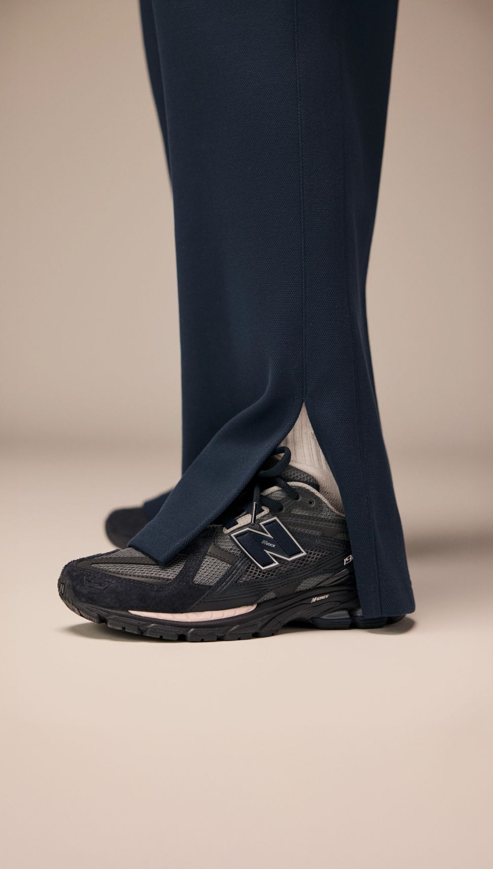 A knee down image of a person against a beige background. 