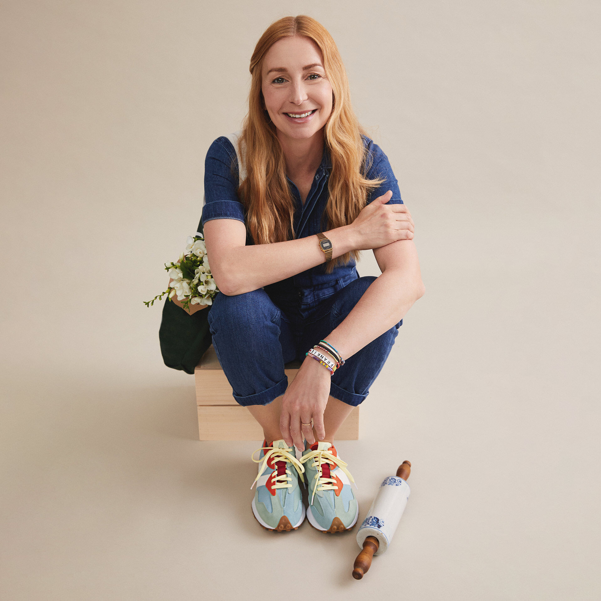 Assise sur une boîte en bois dans un studio, la chef Christina Tosi porte des chaussures 327 oranges et bleu clair