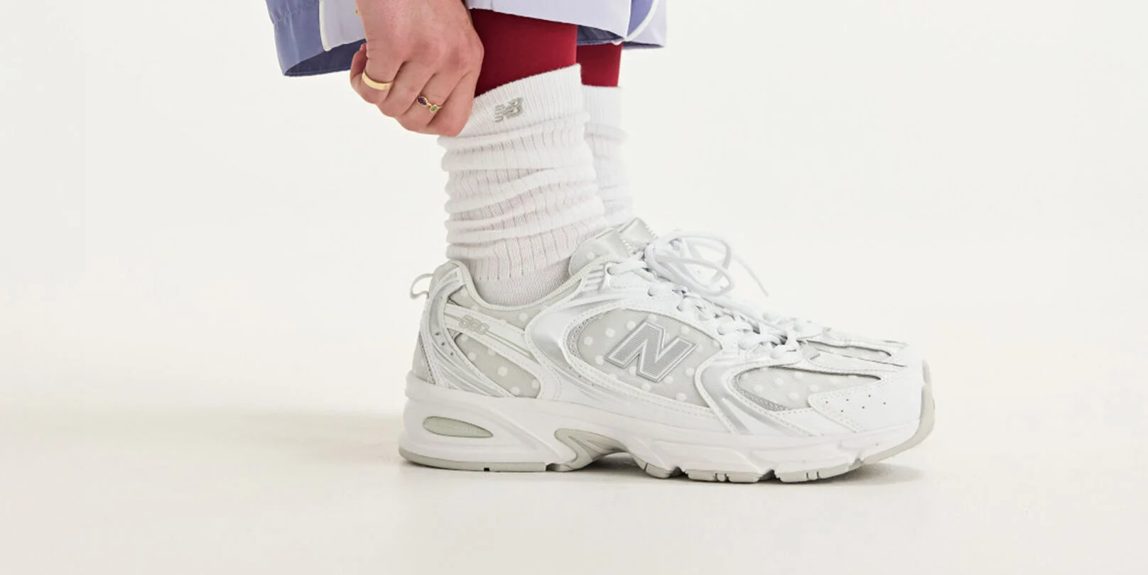 Side view of someone wearing white New Balance sneakers.