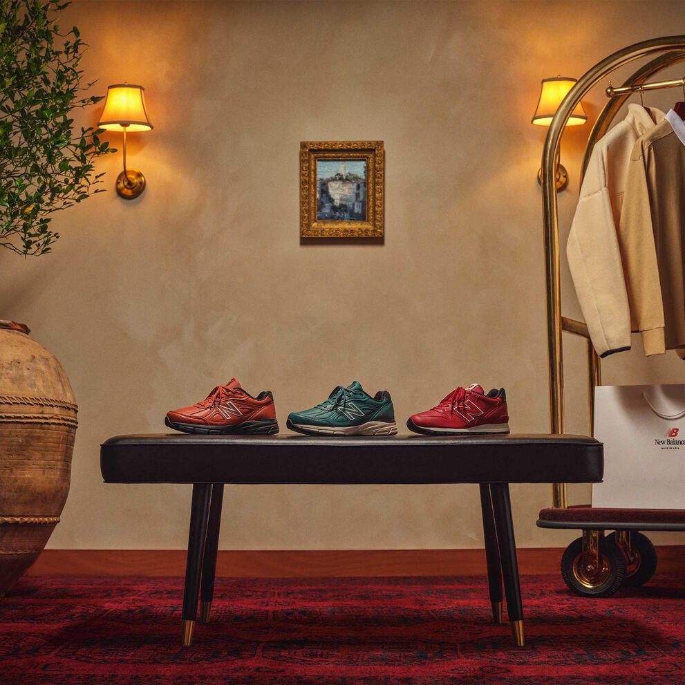 New Balance MADE in USA chaussures, vêtements et boîtes assis ou suspendus sur un panier à bagages doré dans un bel environnement intérieur. 