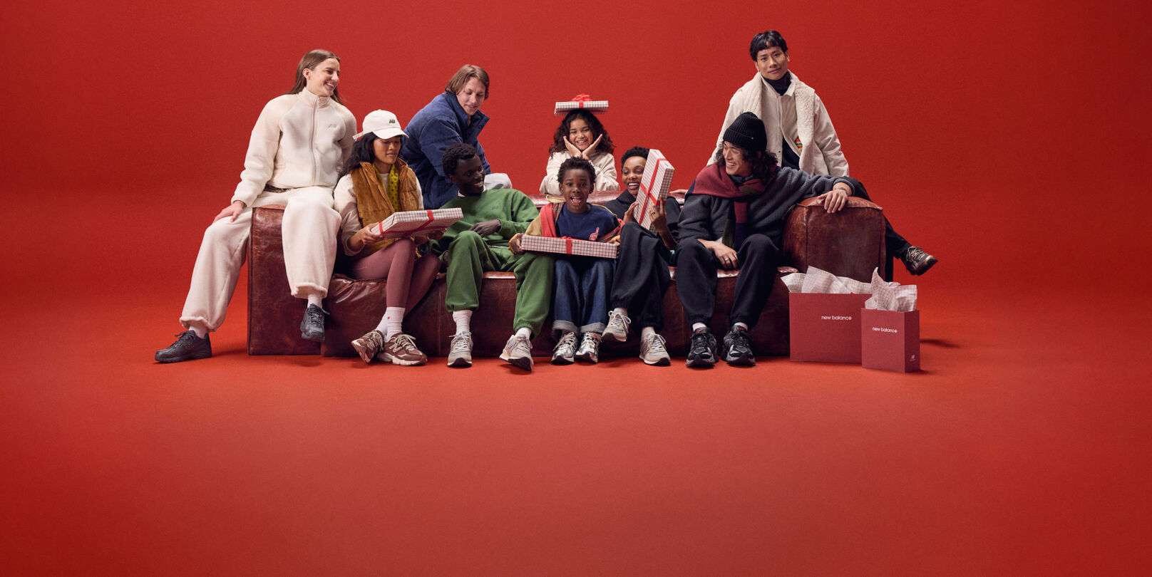 Jeune famille assise sur un canapé rouge avec des cadeaux.