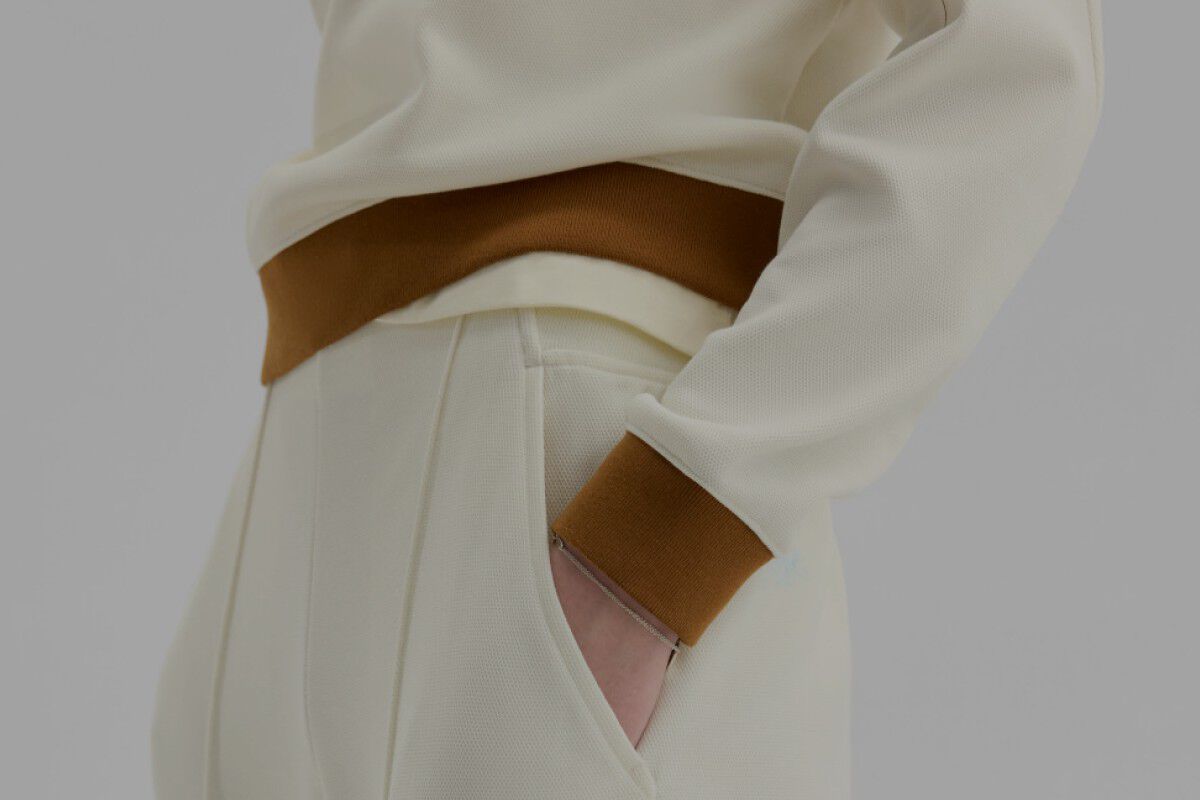 Gros plan de quelqu&rsquo;un portant un pantalon New Balance cr&egrave;me et brun sur un fond blanc.