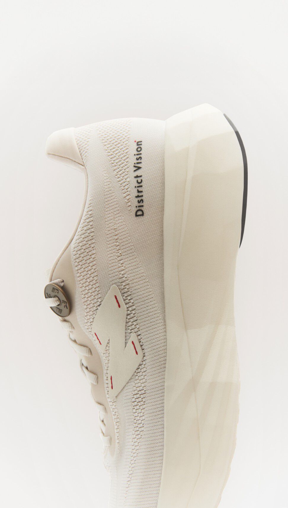 Chaussure District Vision New Balance blanche coupée en deux et photographiée de près à la verticale. 