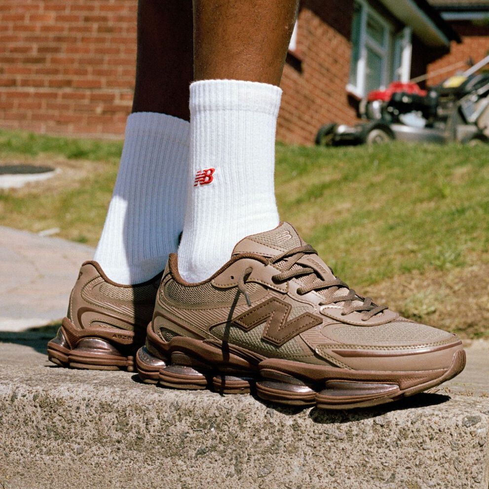 Image genoux contre terre de quelqu&rsquo;un portant des espadrilles New Balance brunes &agrave; l&rsquo;ext&eacute;rieur.