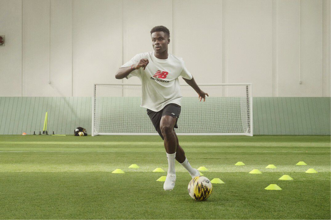 Soccer player dribbling the ball through cones
