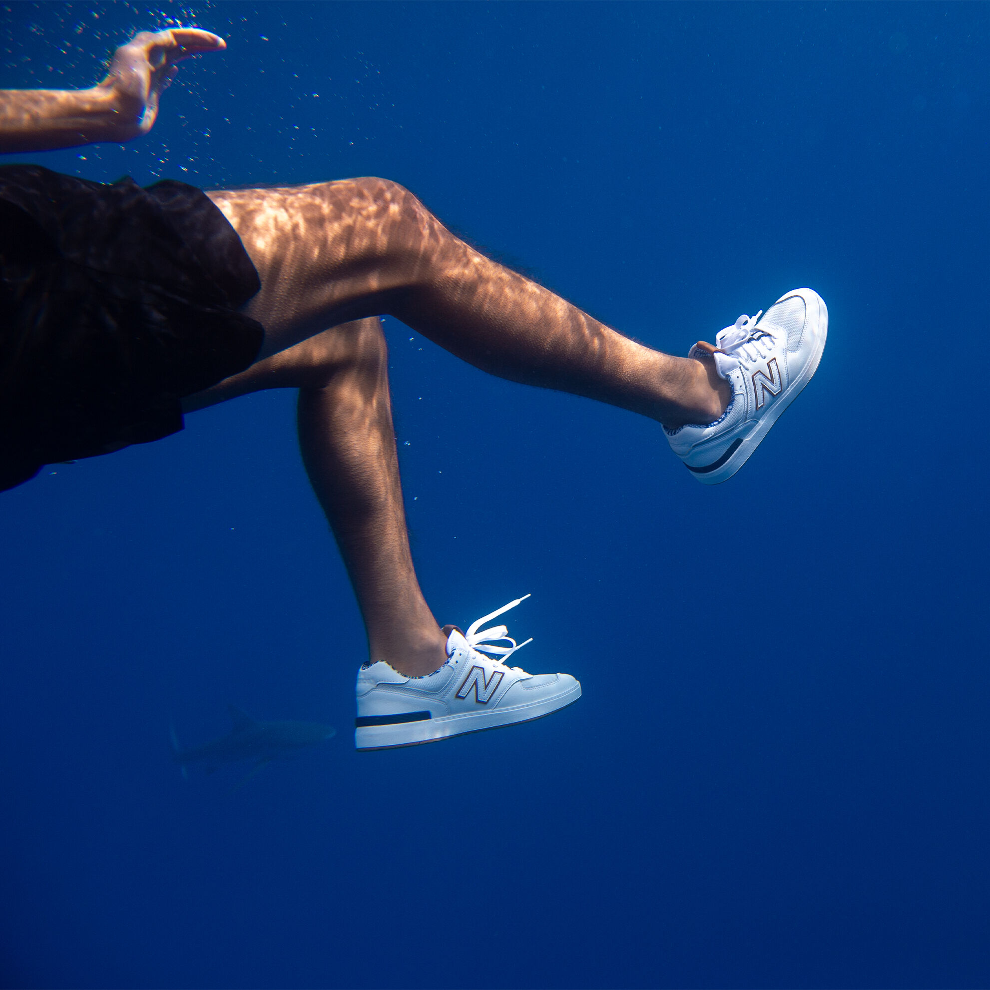 Man swimming with a shark while wearing the AM574 Slowtide