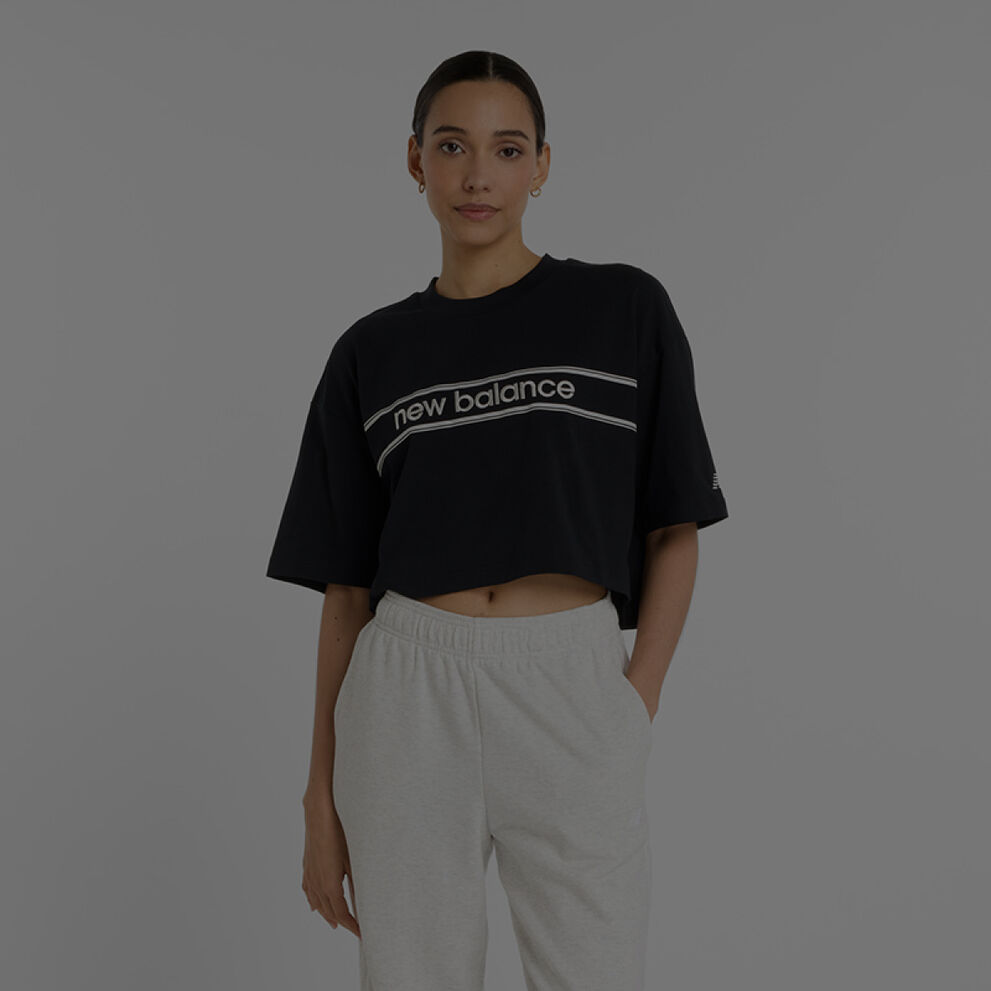 Femme portant un maillot New Balance noir et un survêtement New Balance gris.