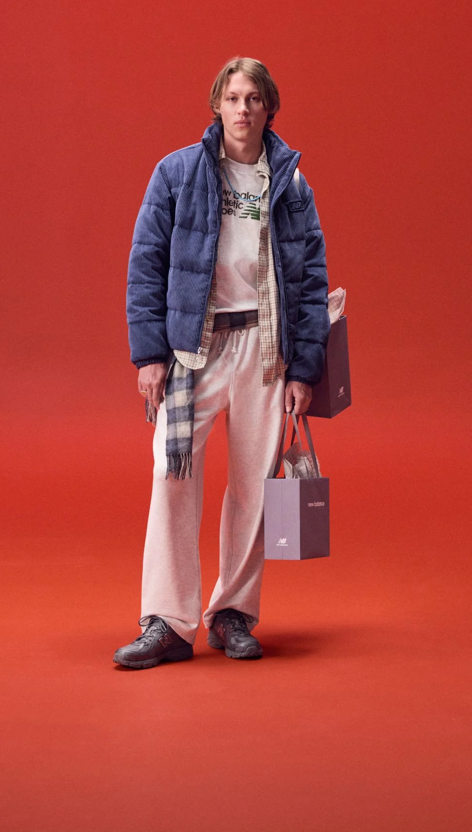 Man in a blue jacket holding a bag on a red background. 