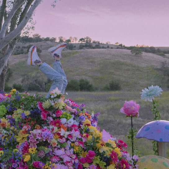 Jaden Smith’s legs sticking out of a pile of flowers with mushrooms around him.