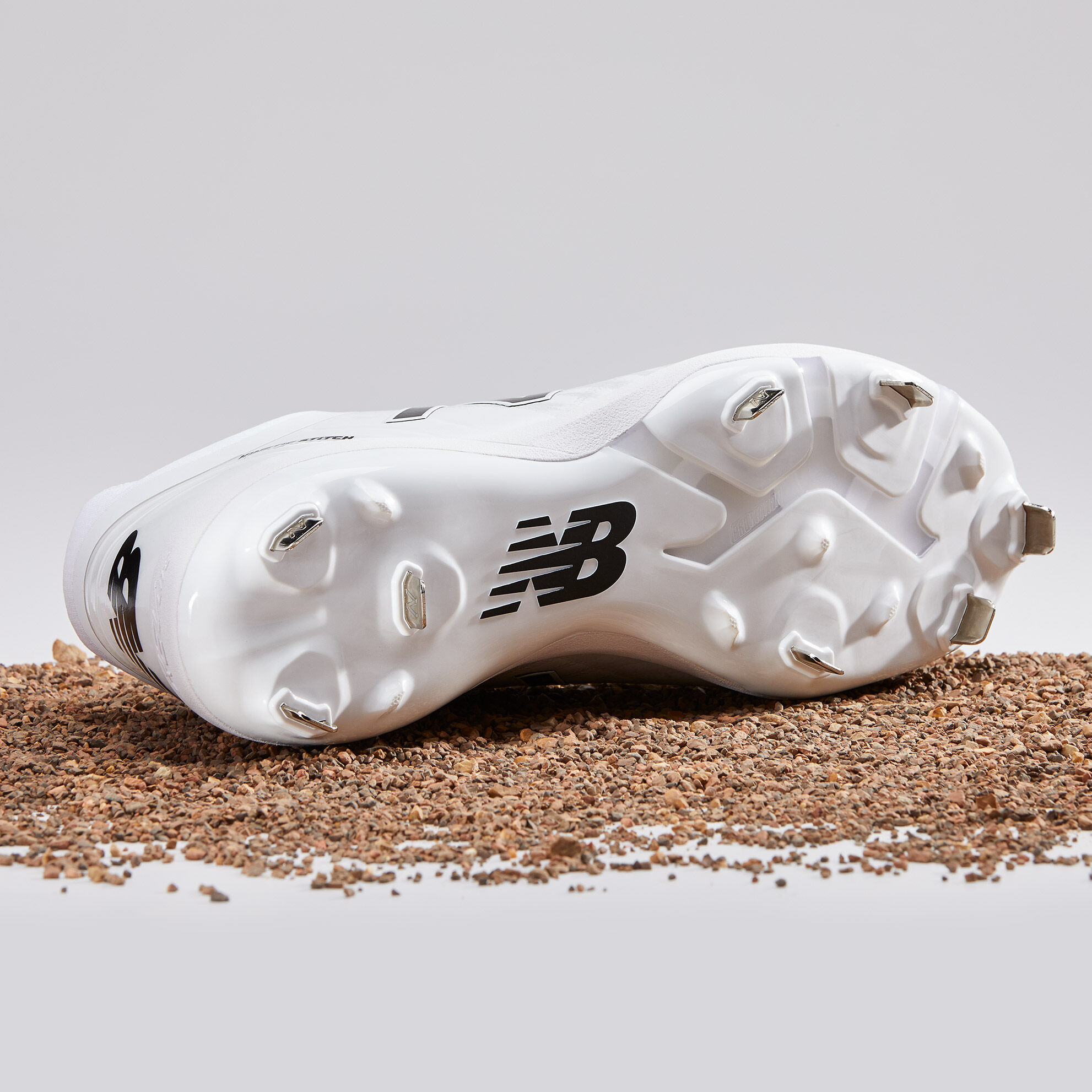 Bottom view of white 4040v4 Metal cleat sitting on gravel