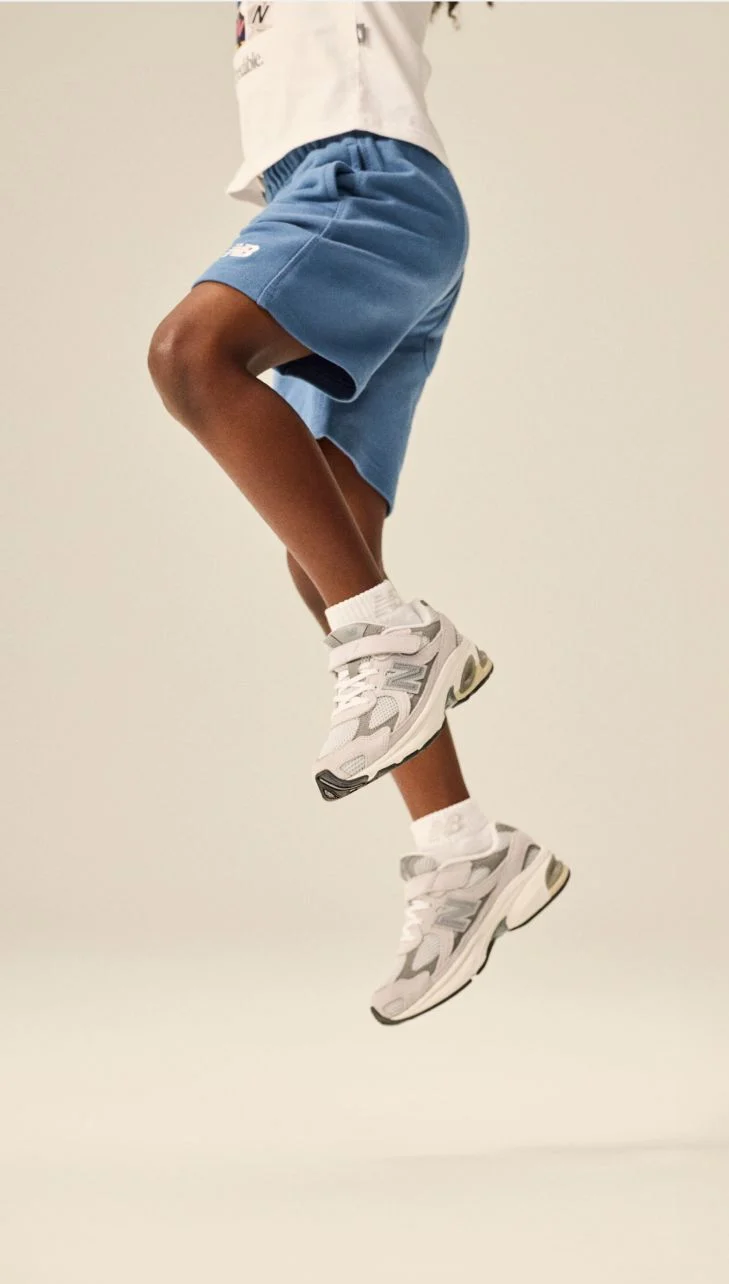 Image d'un enfant, genoux au sol, portant une paire de chaussures 2010.