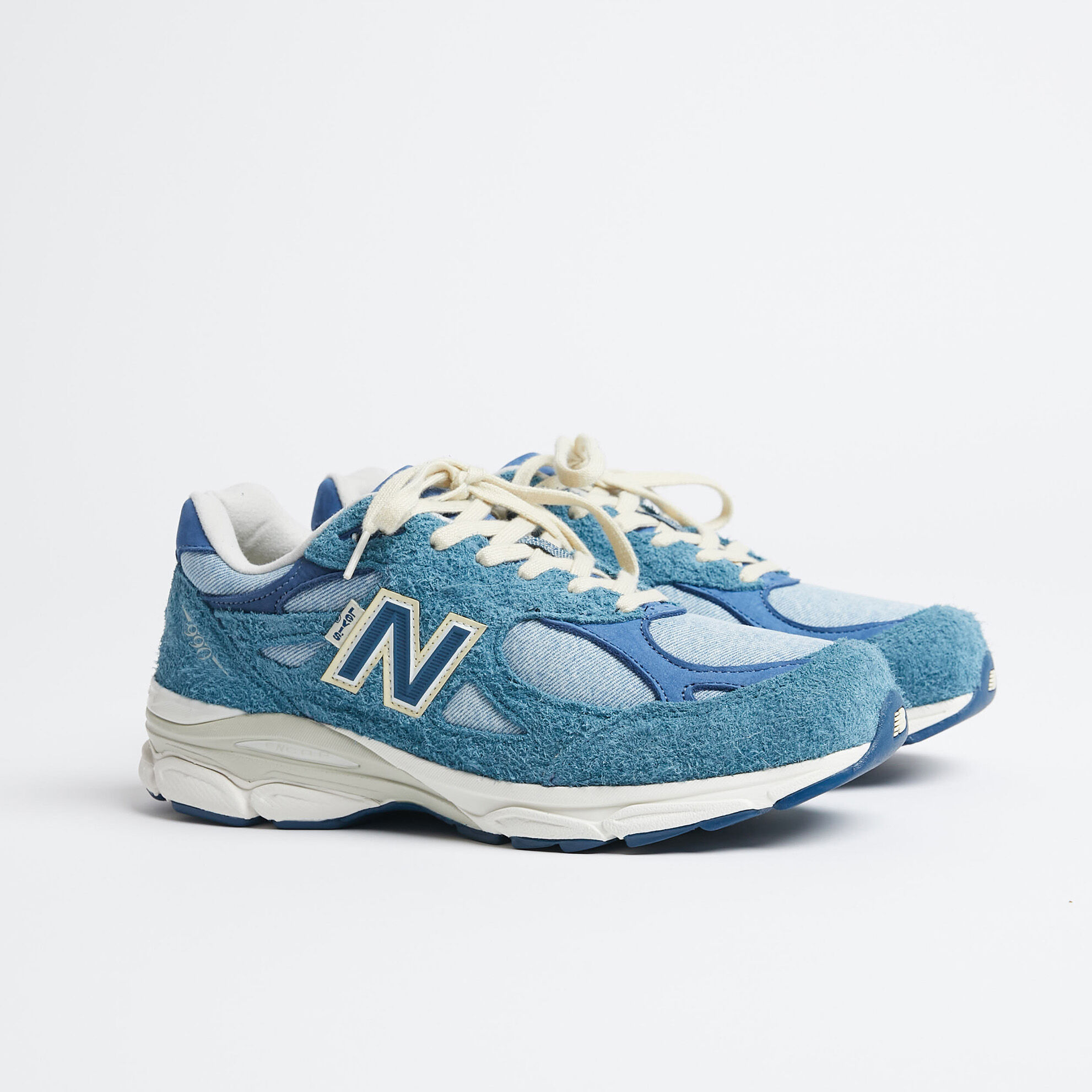 990v3 shoes, one grey and one blue, posed heel to heel in studio environment