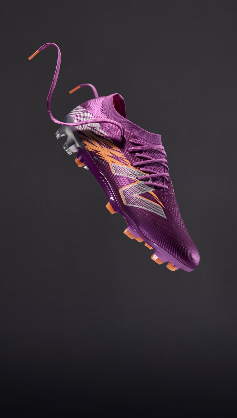 All purple football boot floating in the air on a dark grey background. 