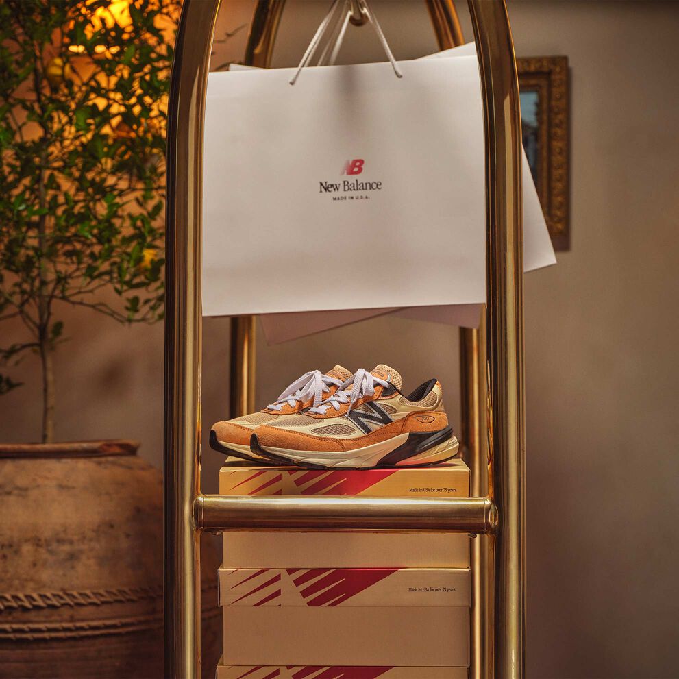 New Balance MADE in USA chaussures et boîtes posés ou suspendus sur un panier à bagages doré dans un bel environnement intérieur. 