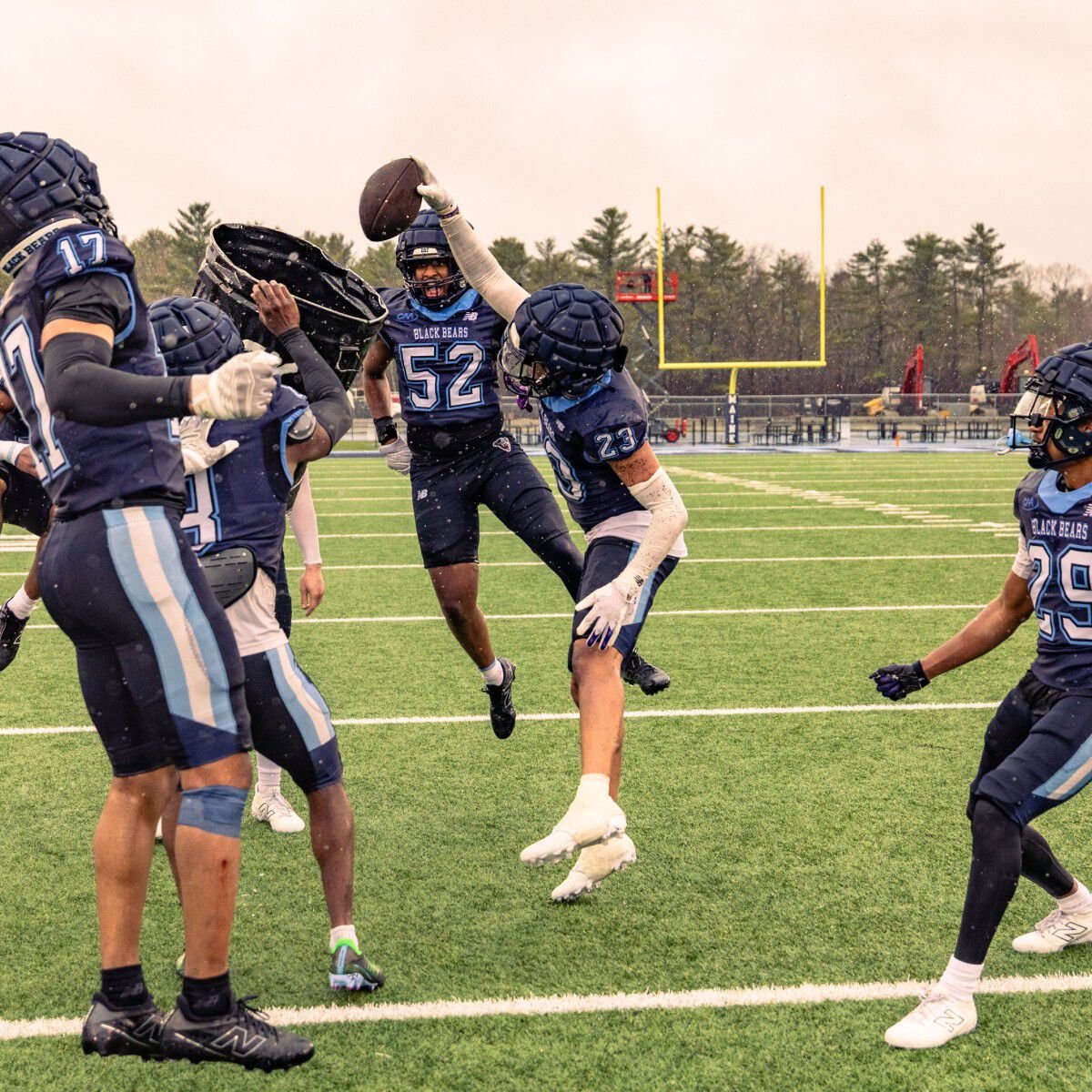Player dunking a football in a trash can on the field in full gear.