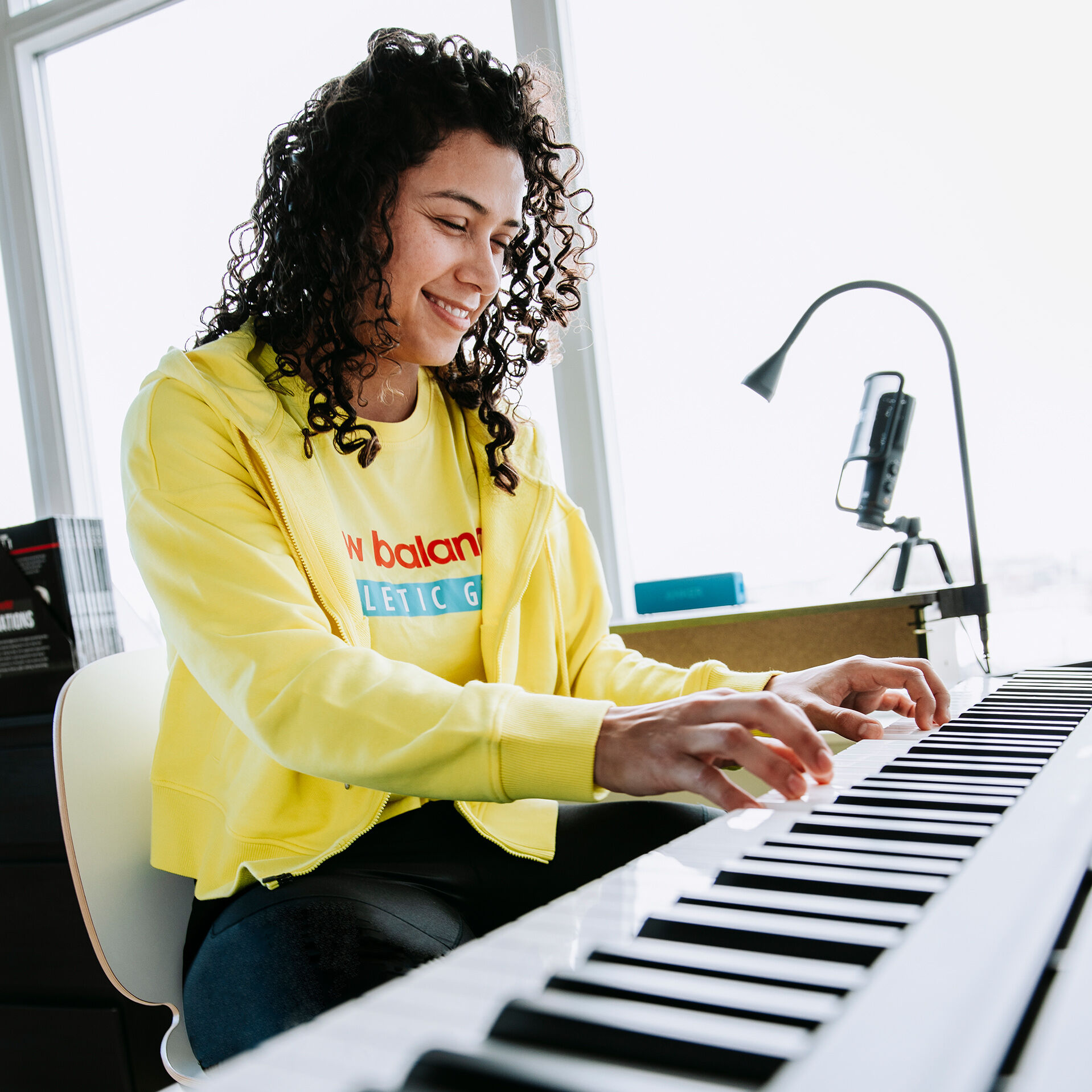 Rocky Rodriguez sitting and playing the piano in yellow shirt and jacket 