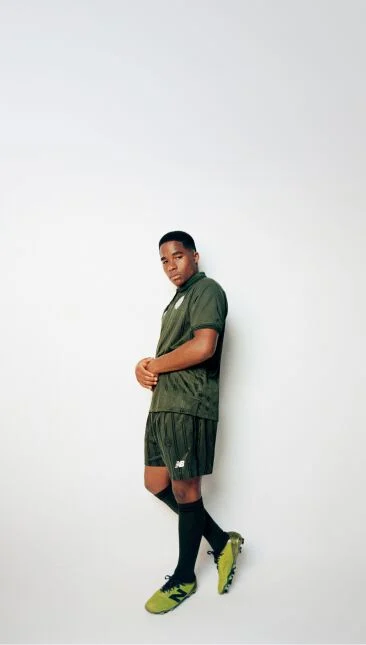Endrick leaning against a wall wearing a green soccer uniform with his arms together