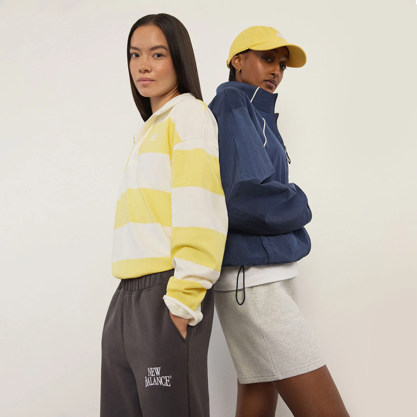 Deux femmes debout devant un mur blanc.