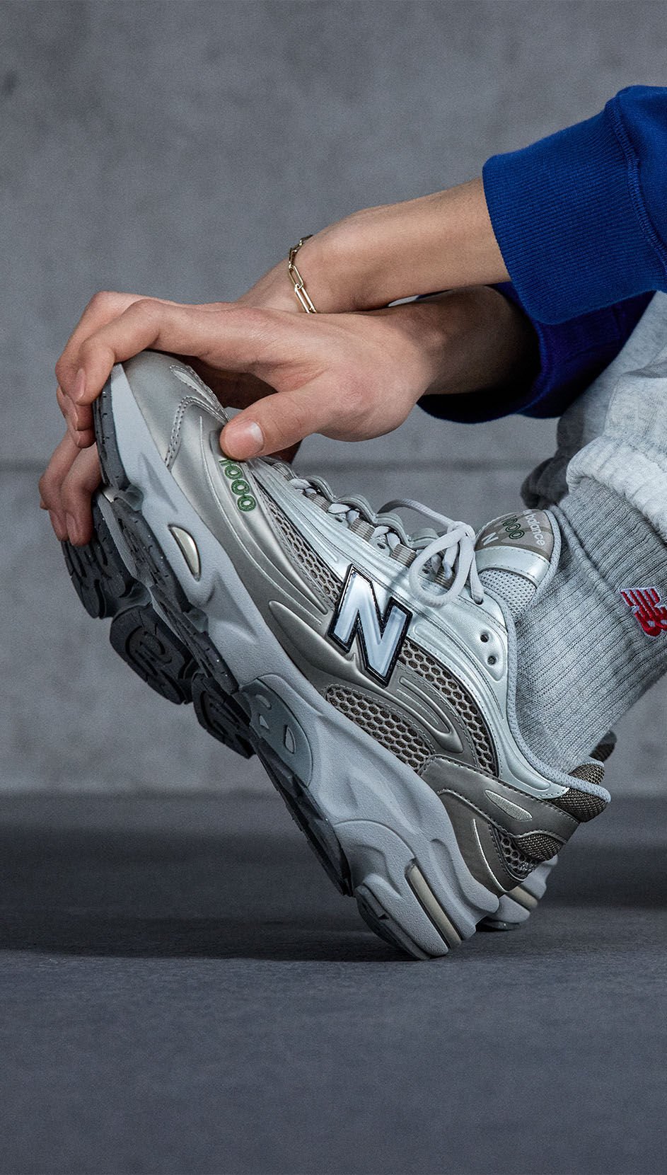 Une image prise à genoux d'un individu portant une paire d'espadrilles New Balance 1000