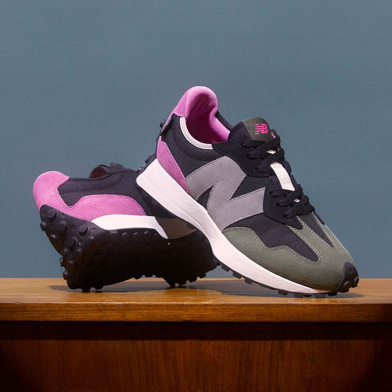 Pair of 327 shoes in pink, black, grey and olive propped up on top of a vintage desk