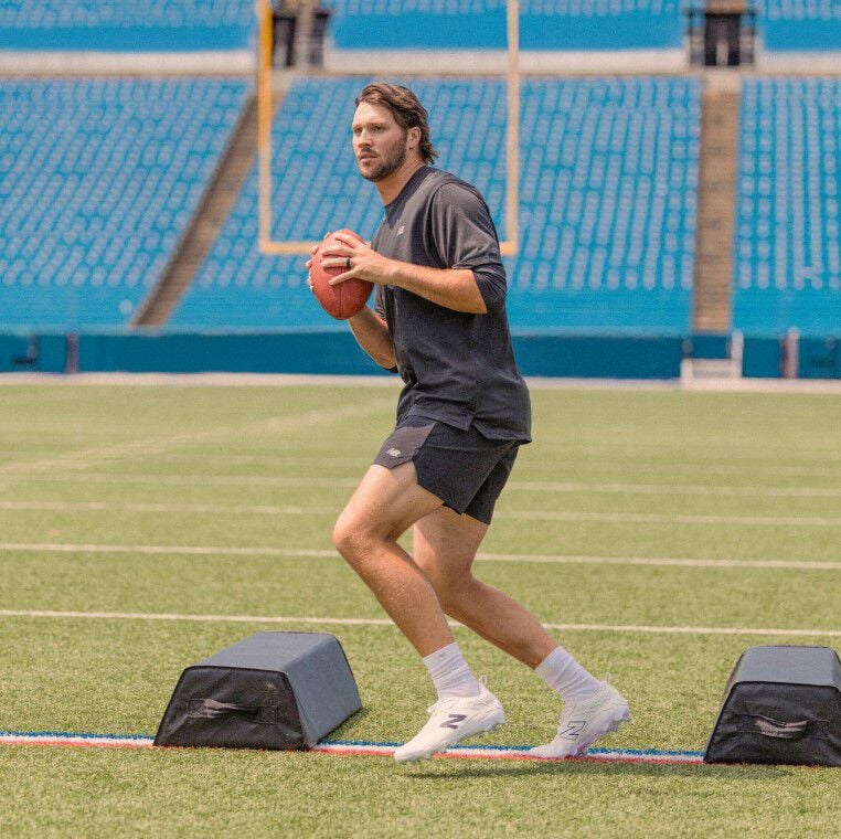 Football player ready to throw a football wearing white cleats