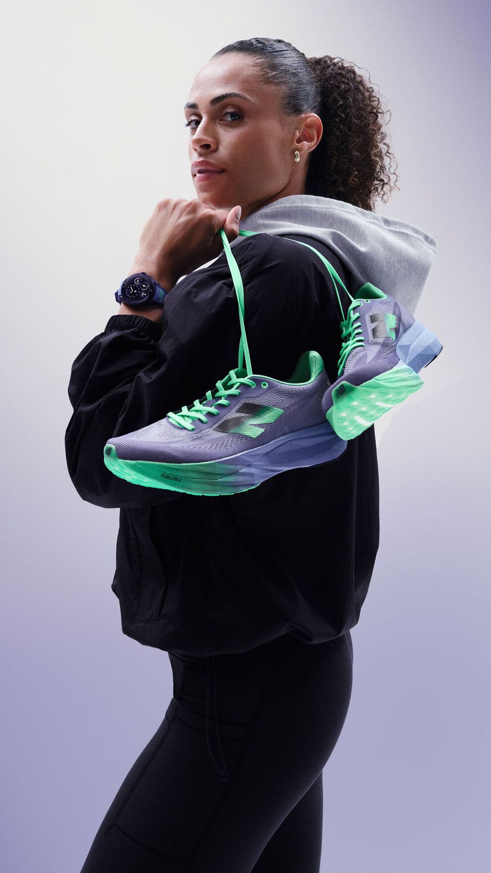 Sydney McLaughlin-Levrone holding a pair of shoes over her shoulder and looking towards the viewer. 