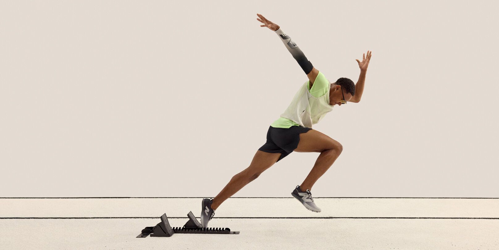 A sprinter is captured mid-stride launching from starting blocks on a track. 
