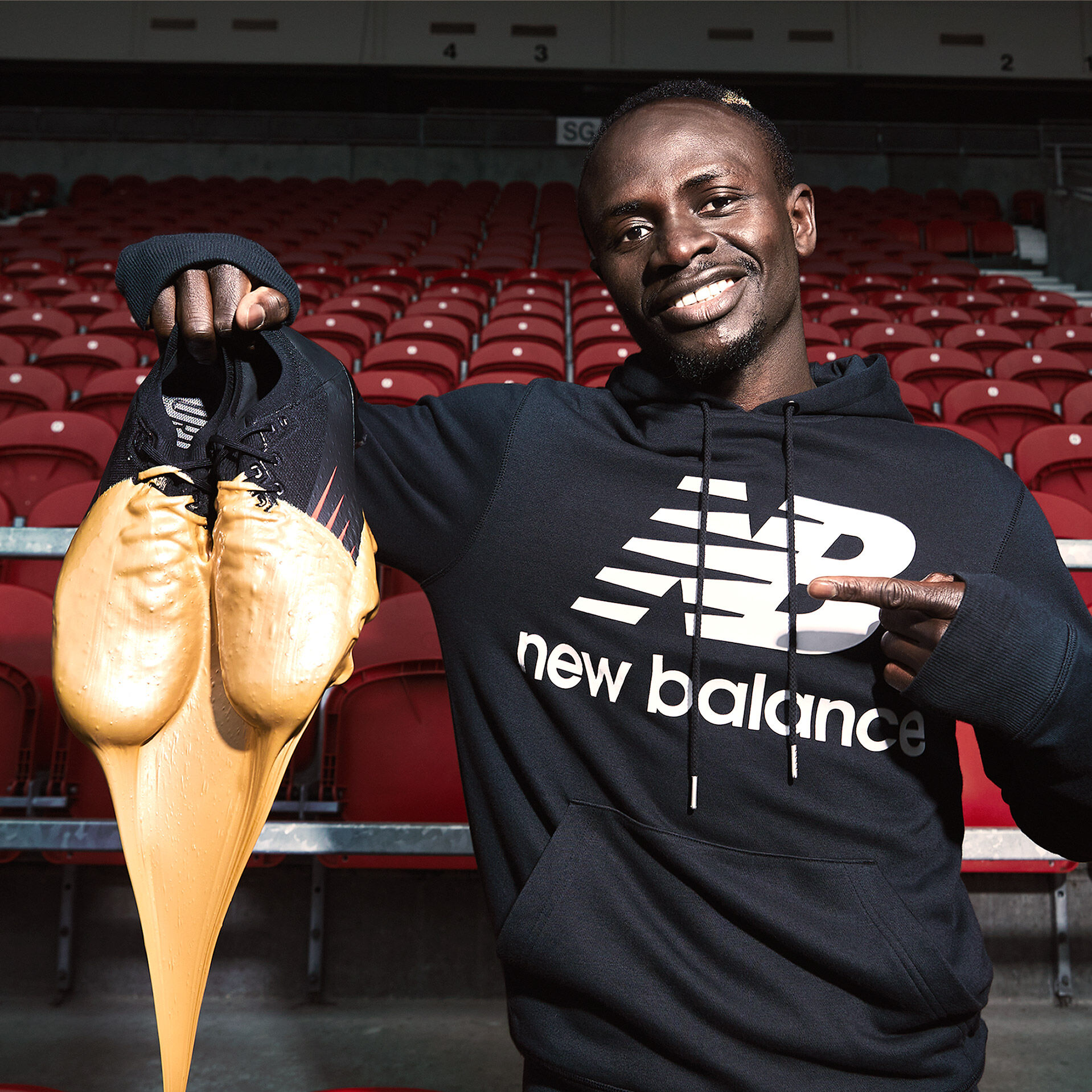 Footballer Sadio Mane holding gold-dipped boots