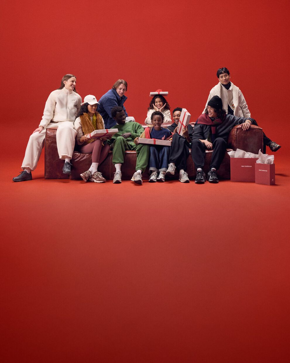 Jeune famille assise sur un canapé rouge avec des cadeaux.