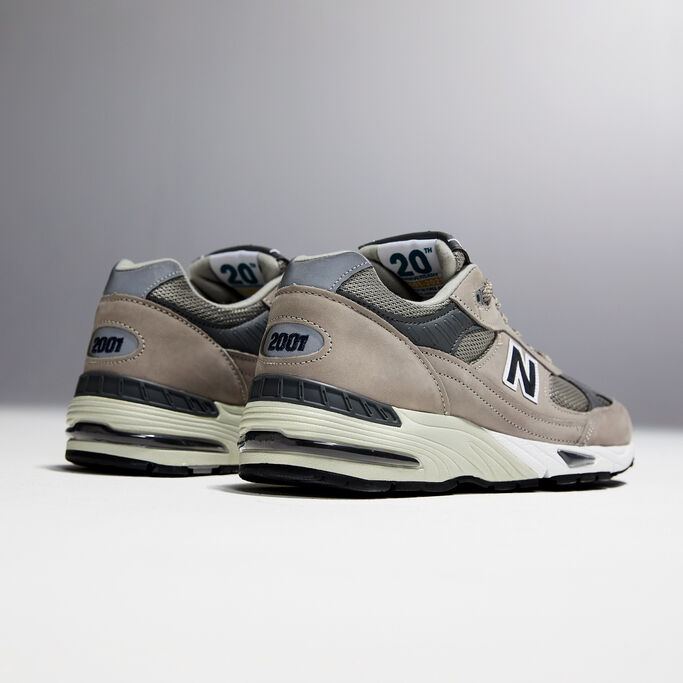 A ¾ angle studio shot of the heels of a pair of men’s grey NB 991 sneakers