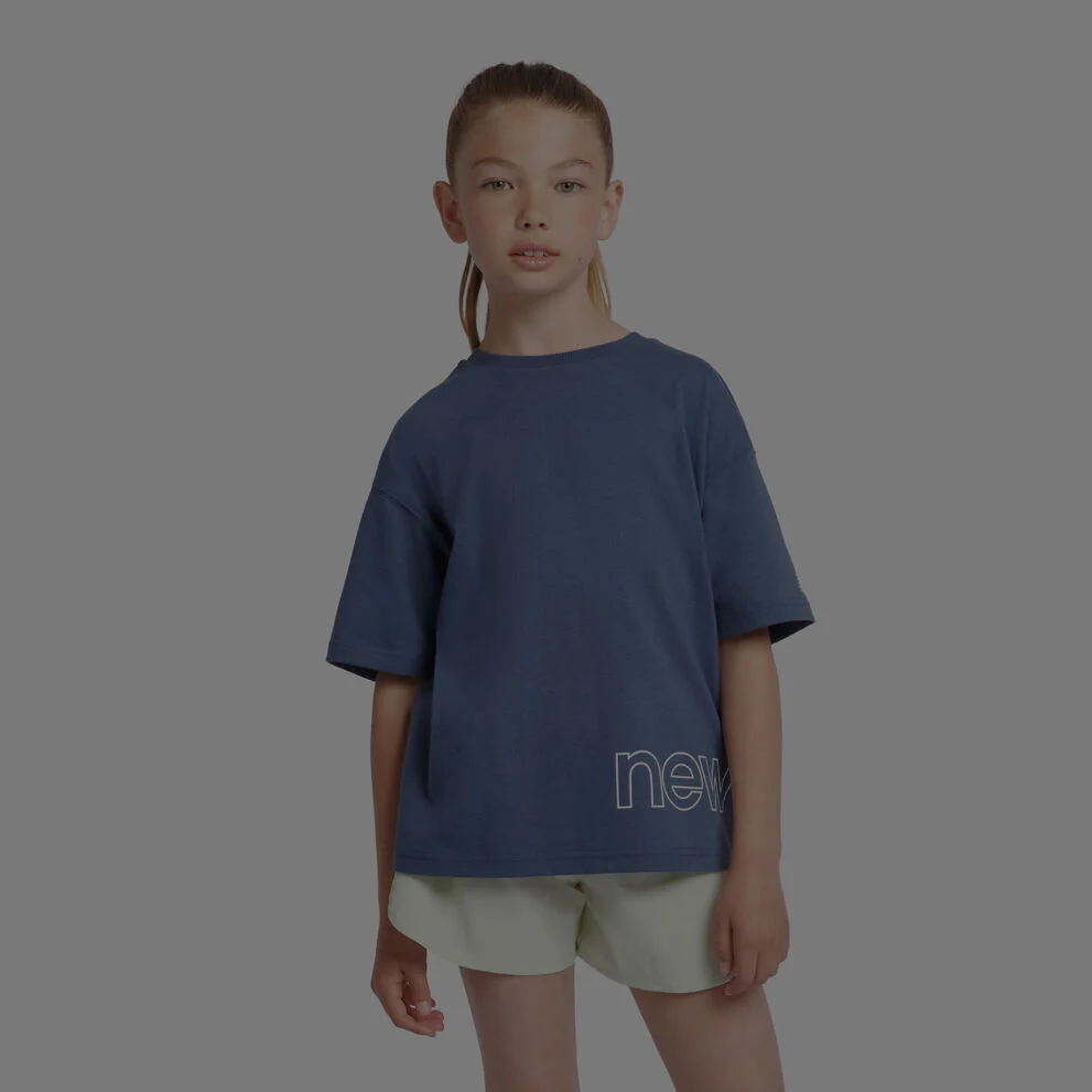 Enfant portant un maillot New Balance bleu sur fond gris.