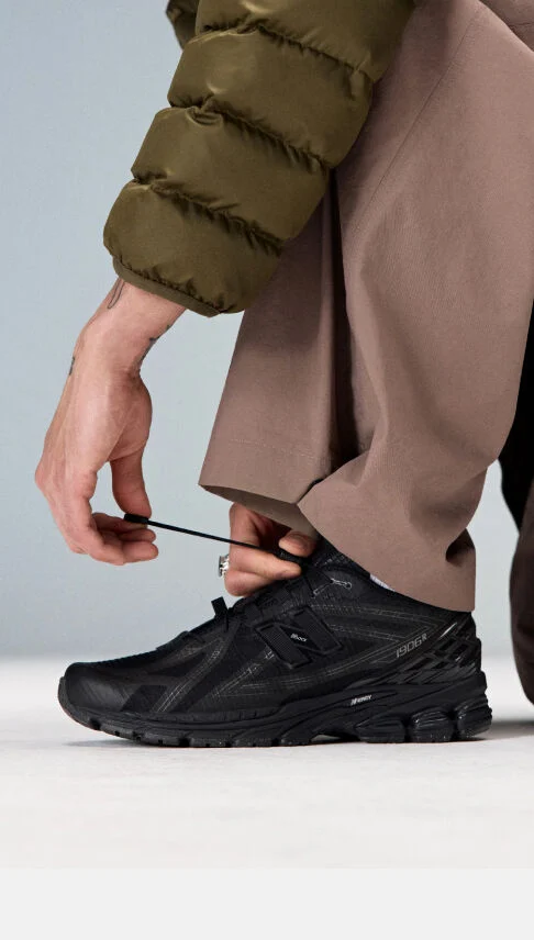 Closeup of an individual kneeling down to tie the laces on the 1906R 