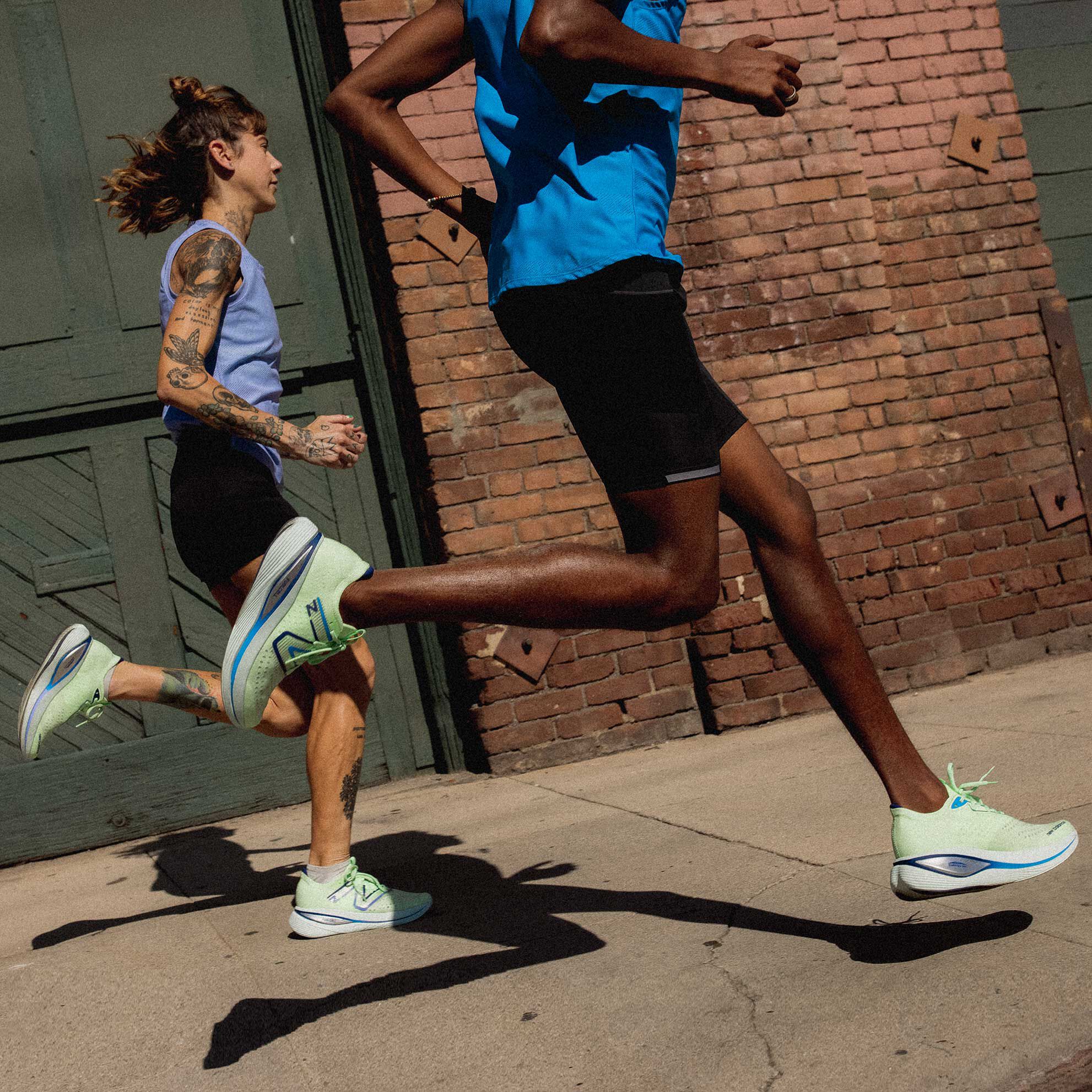 Homme et femme marchant sur le trottoir du genou vers le bas avec des FuelCell SuperComp Trainer v1.
