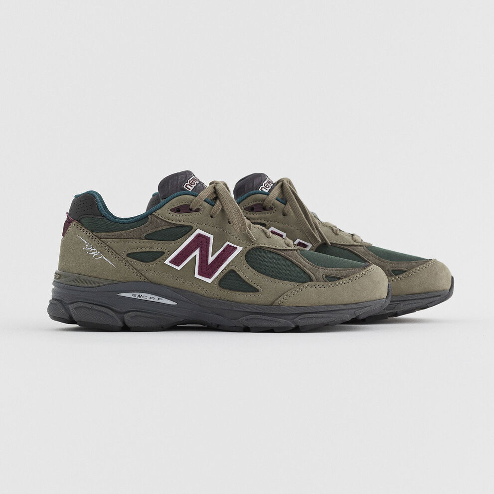Une paire de 990v3 brun assis dans un environnement de studio gris.