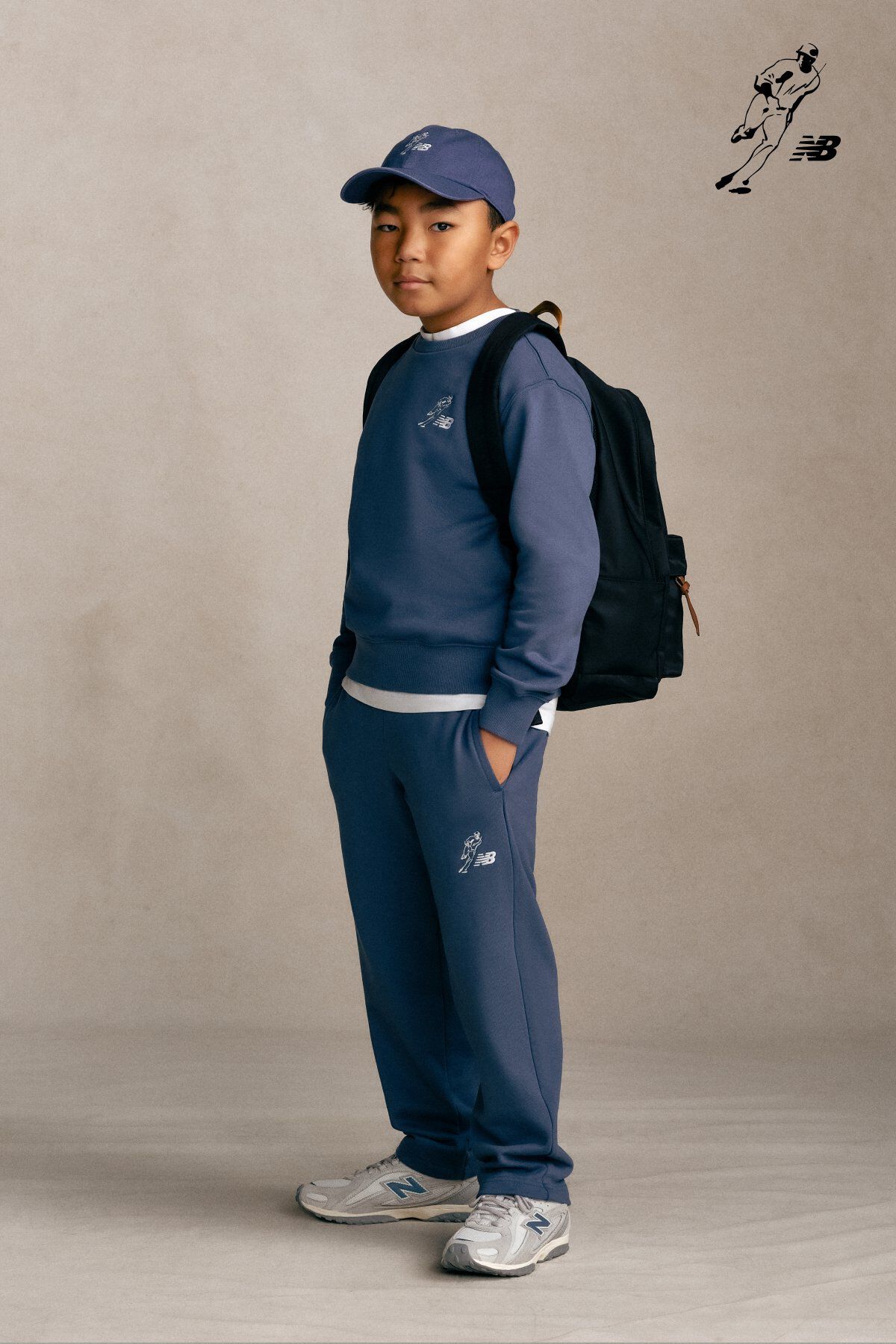 Un enfant debout devant un fond gris de studio.