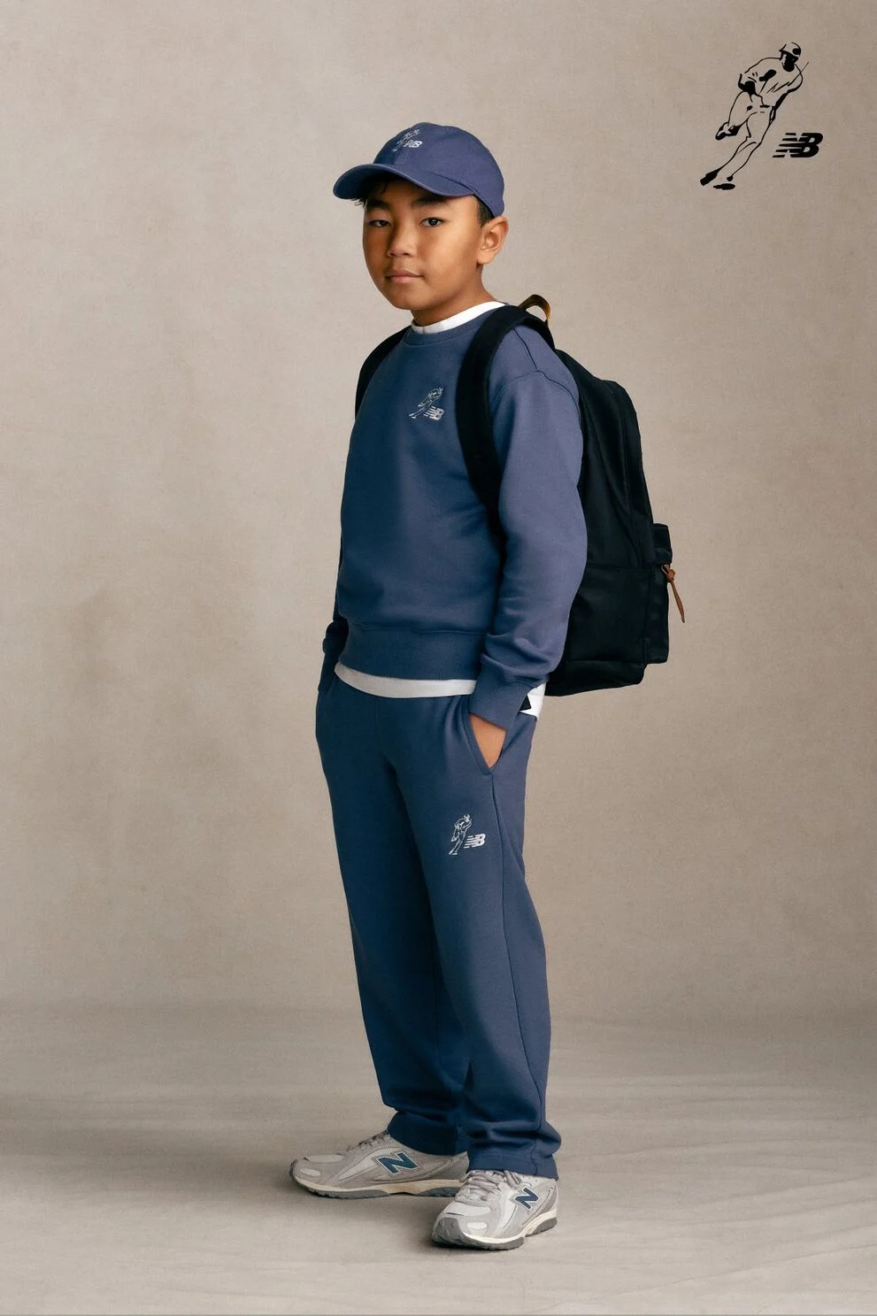 Un enfant debout devant un fond gris de studio.
