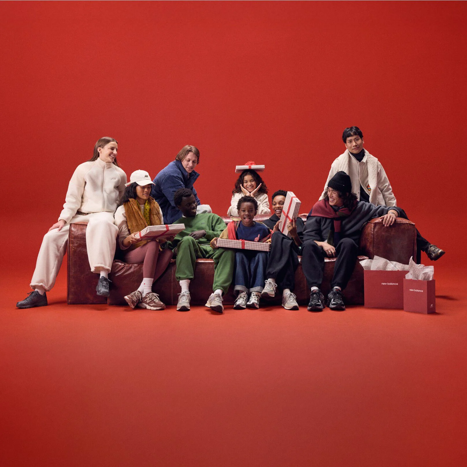 Young family sitting on a red couch holding gifts.