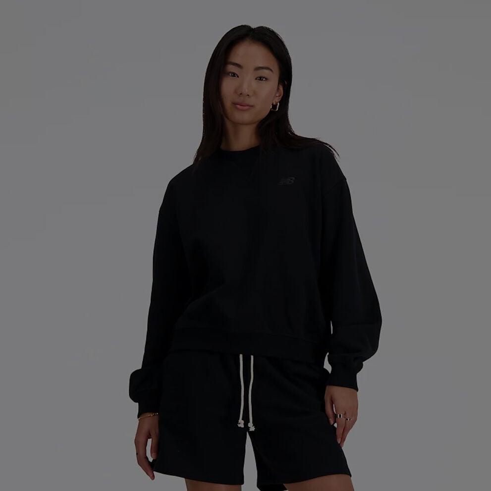 Femme vêtue d'un t-shirt New Balance noir à manches longues et d'un short noir assorti.