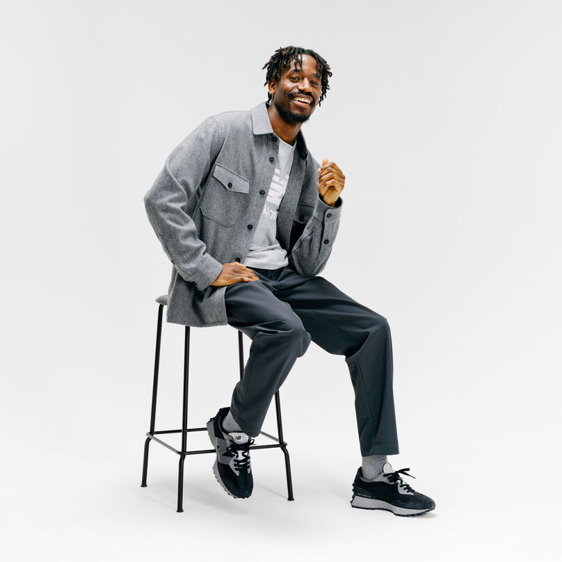 Homme assis sur un tabouret dans un décor de studio gris, portant les baskets Grey Day 327.