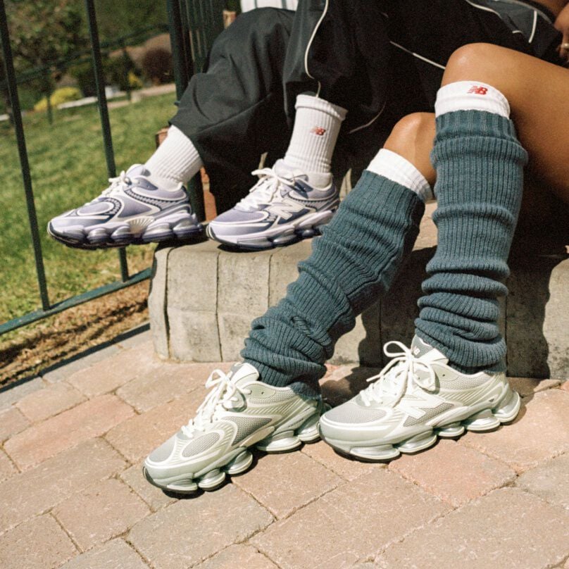 Deux personnes assises sur un trottoir portant des baskets New Balance.