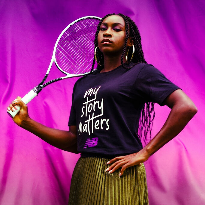 Coco Gauff holding tennis racket and wearing My Story Matters tshirt against velvet backdrop.