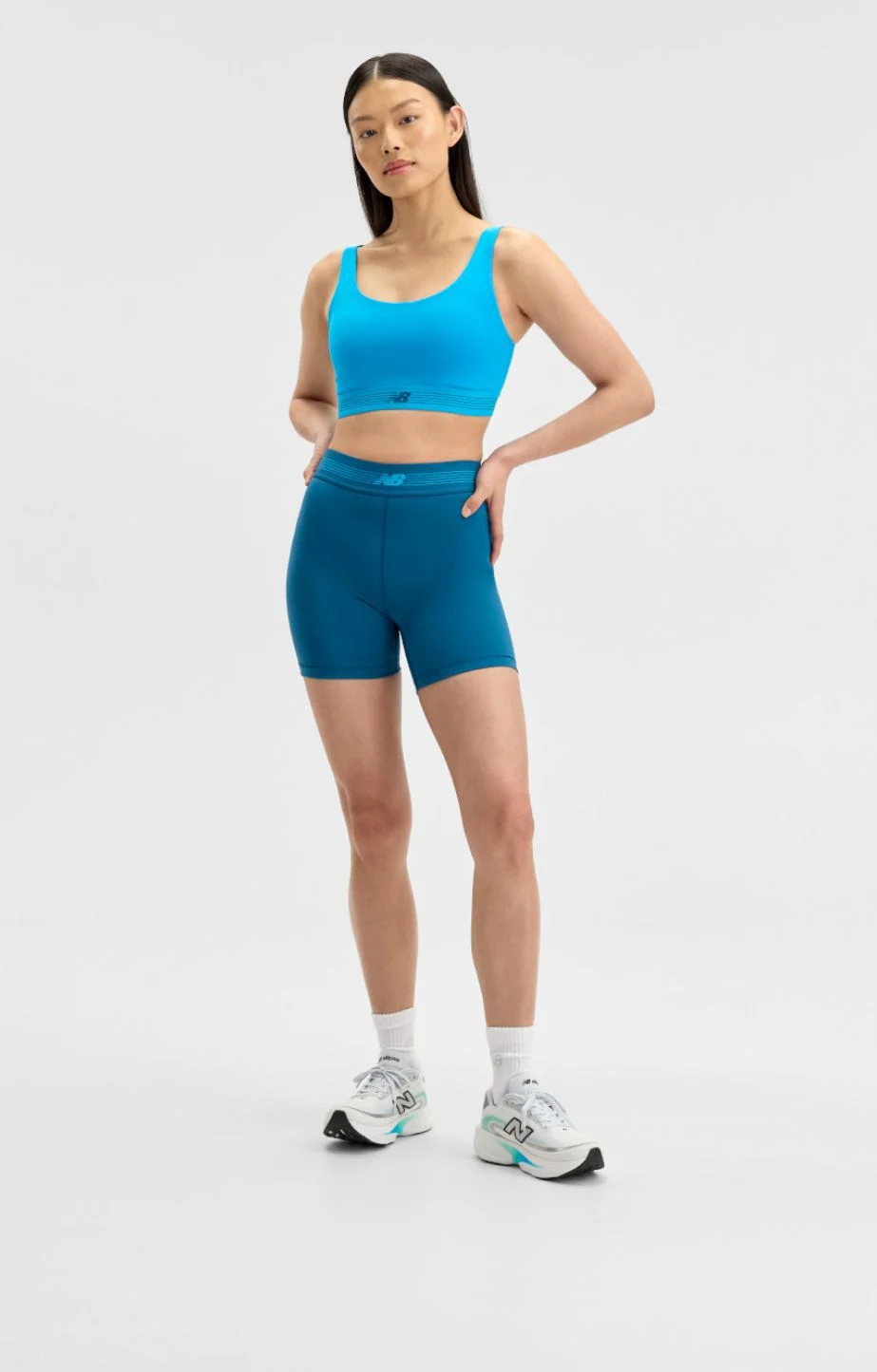 femme portant des v&ecirc;tements New Balance bleus sur un fond blanc.