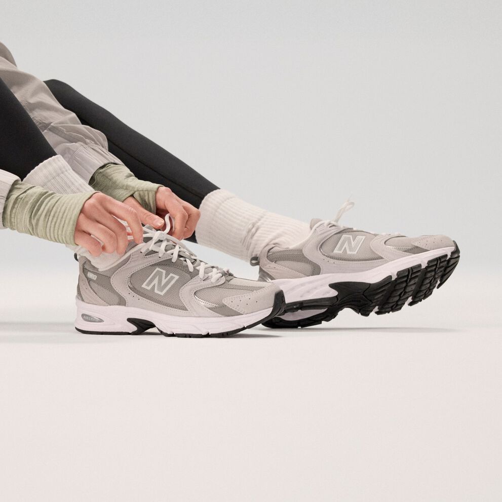 Mannequin portant des chaussures gris pâle sur fond gris.