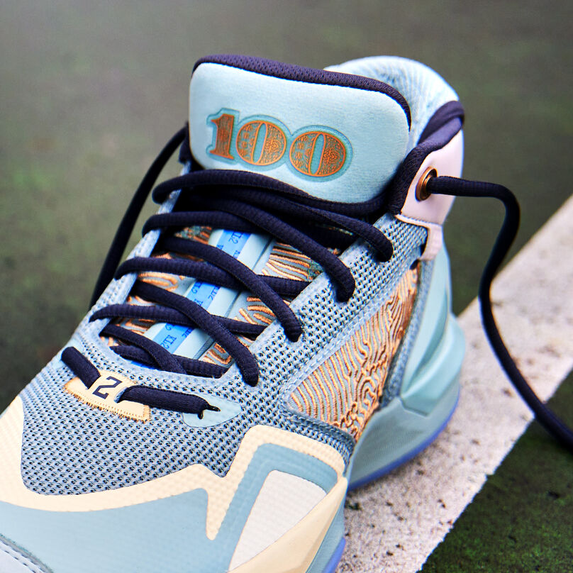 Cropped, front facing view of the light green KAWHI “New Money” inspired signature shoe, showing the laces and tongue details, sitting on a wet