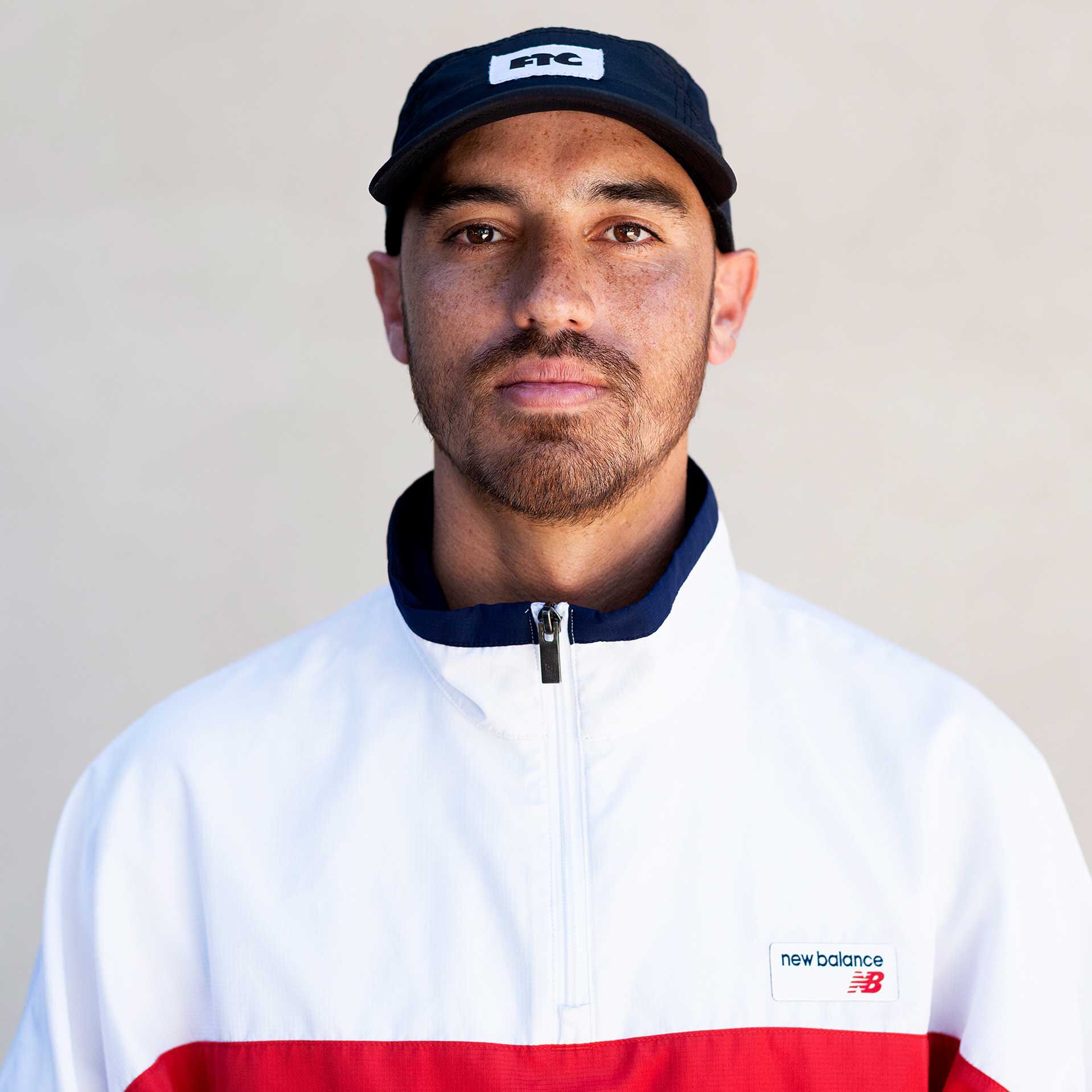 Skateboarder JP Souza in a bus seat, wearing a black graphic tee and white retro snapback