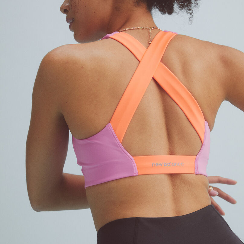 Back view of a woman wearing a pink and orange NB Fuel bra with black leggings