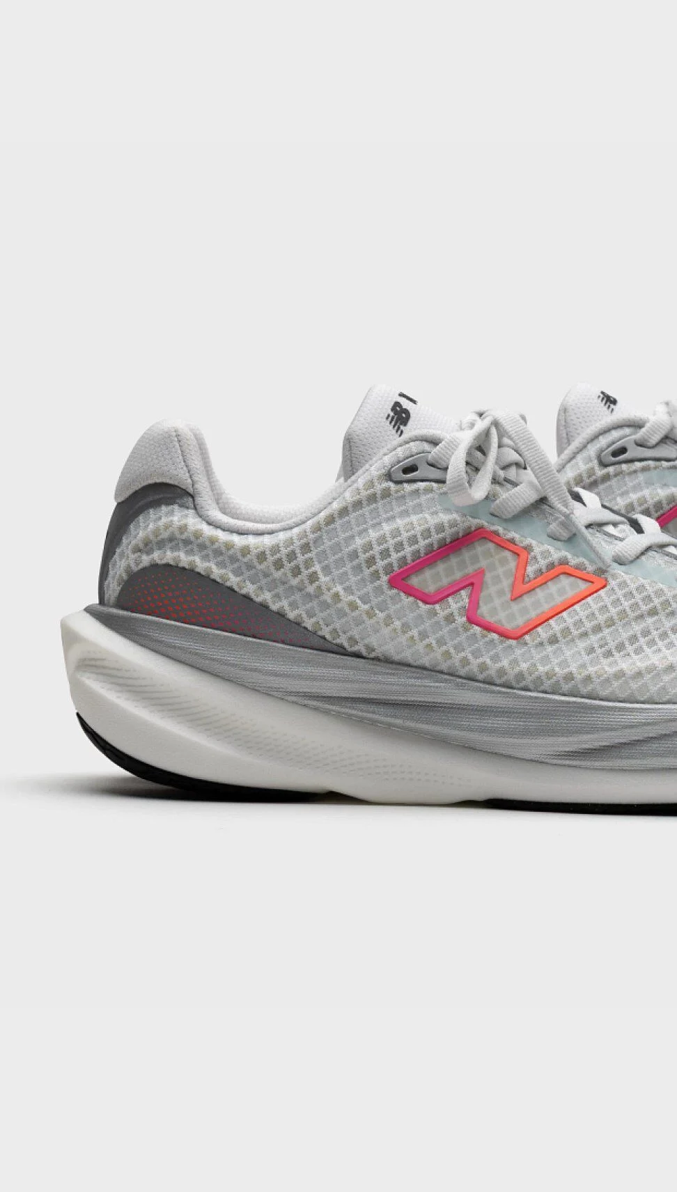 Vue lat&eacute;rale recadr&eacute;e d&rsquo;une chaussure de course New Balance gris p&acirc;le sur un arri&egrave;re-plan neutre, mettant en valeur la tige en filet, la semelle intercalaire sculpt&eacute;e et le logo &laquo; N &raquo; en d&eacute;grad&eacute;.&nbsp;