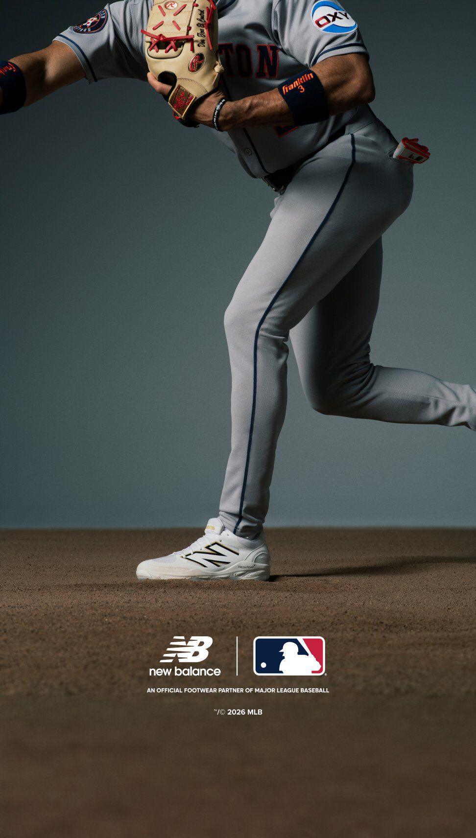 A baseball player wearing a gray uniform with navy and orange accents is positioned in a ready stance, holding a tan glove with red stitching.