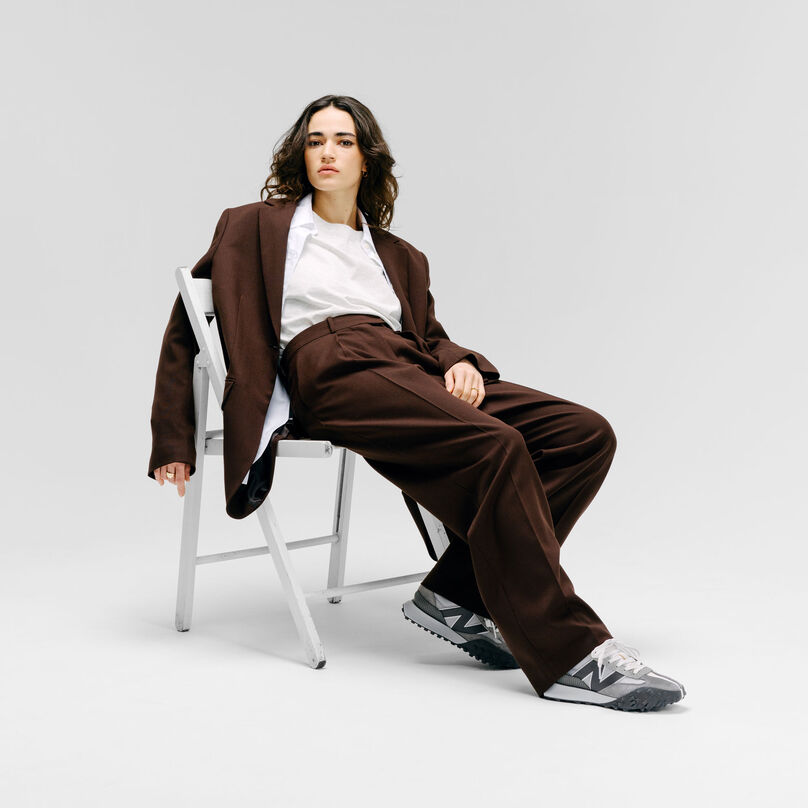 Femme assise sur une chaise dans un décor de studio gris et portant des Grey Day XC-72